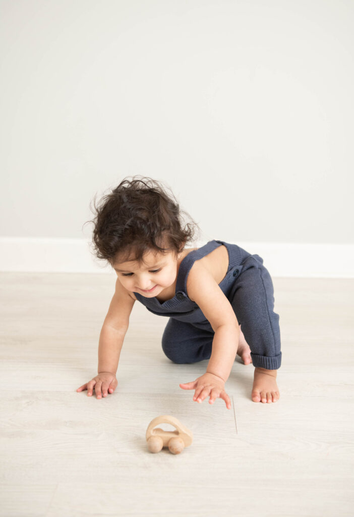 one year old playing with wooden car in studio