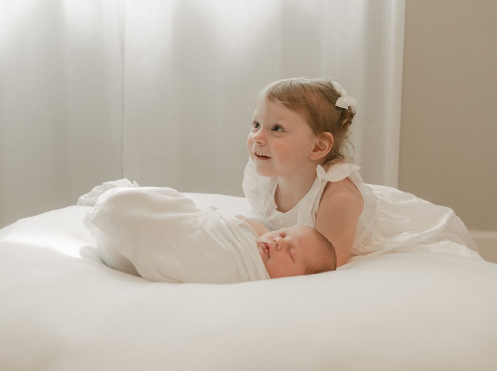 A young girl lays on a large bean bag with her newborn baby sibbling king of prussia doulas