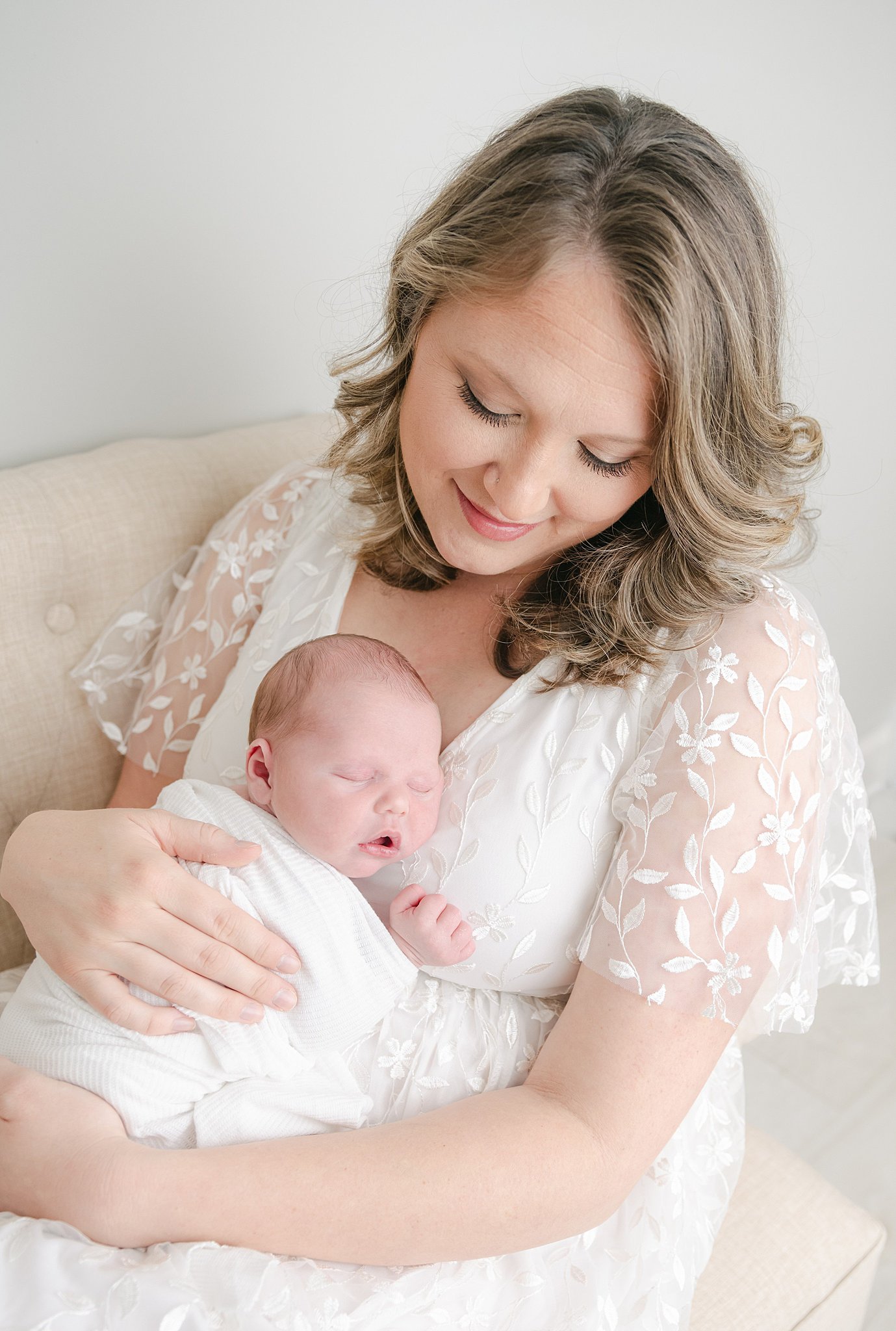 A newborn baby sleeps on its mom's chest who is wearing a white lace dress women and babies hospital lancaster