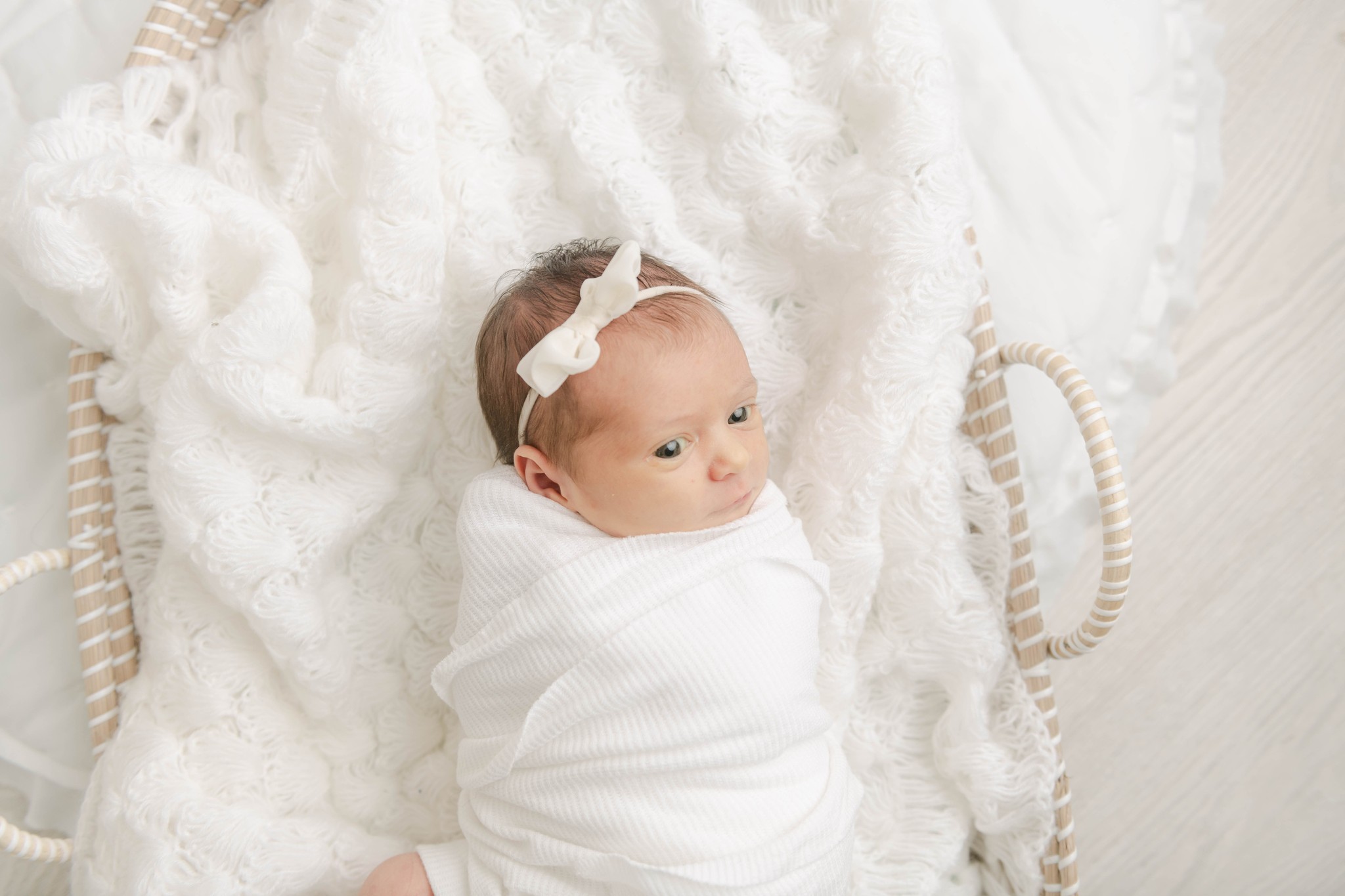A newborn baby looks around while laying in a woven basket in a swaddle baby shower venues lancaster pa