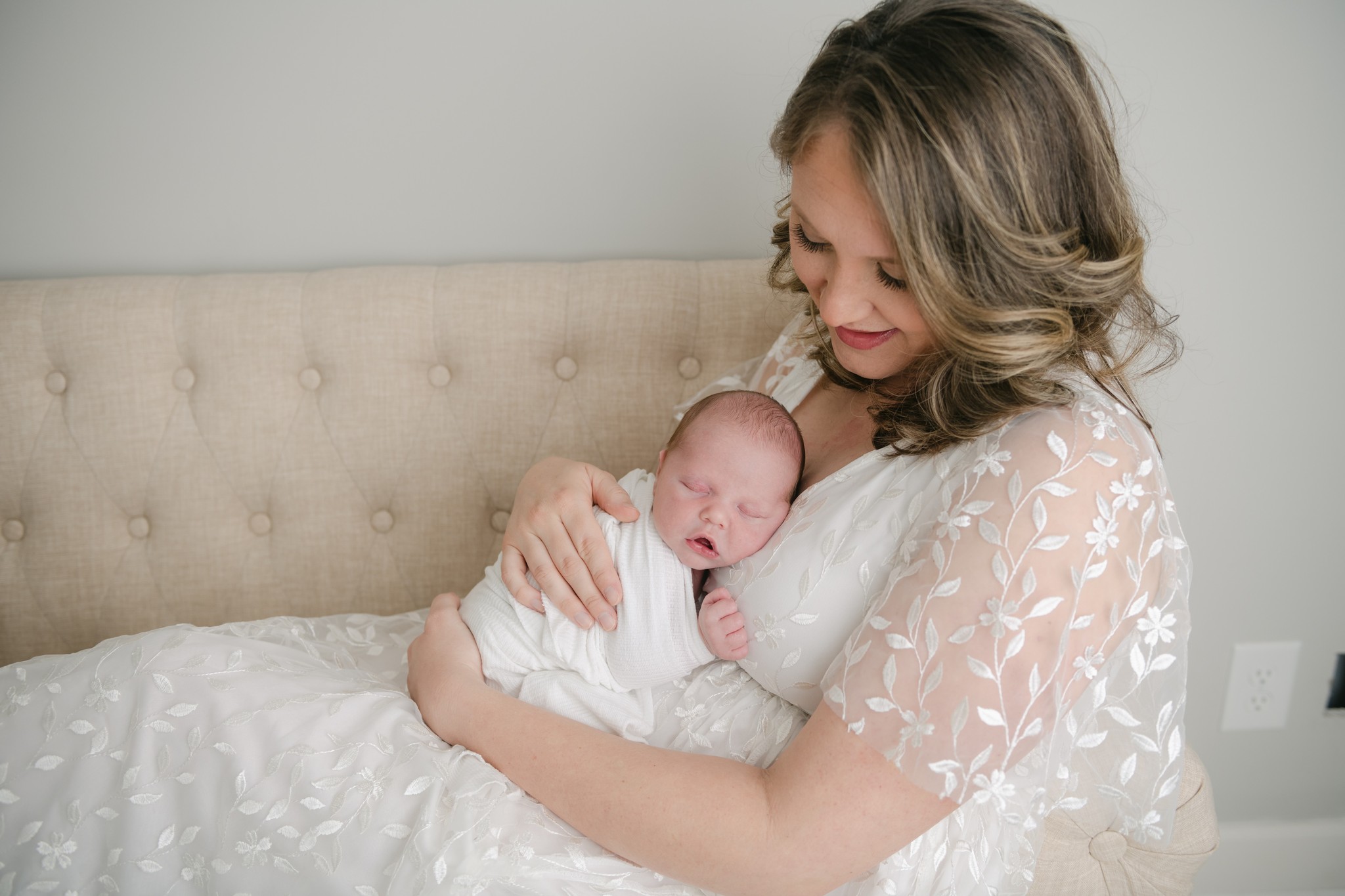 A new mother sits across a couch cradling her newborn baby on her chest prenatal massage king of prussia