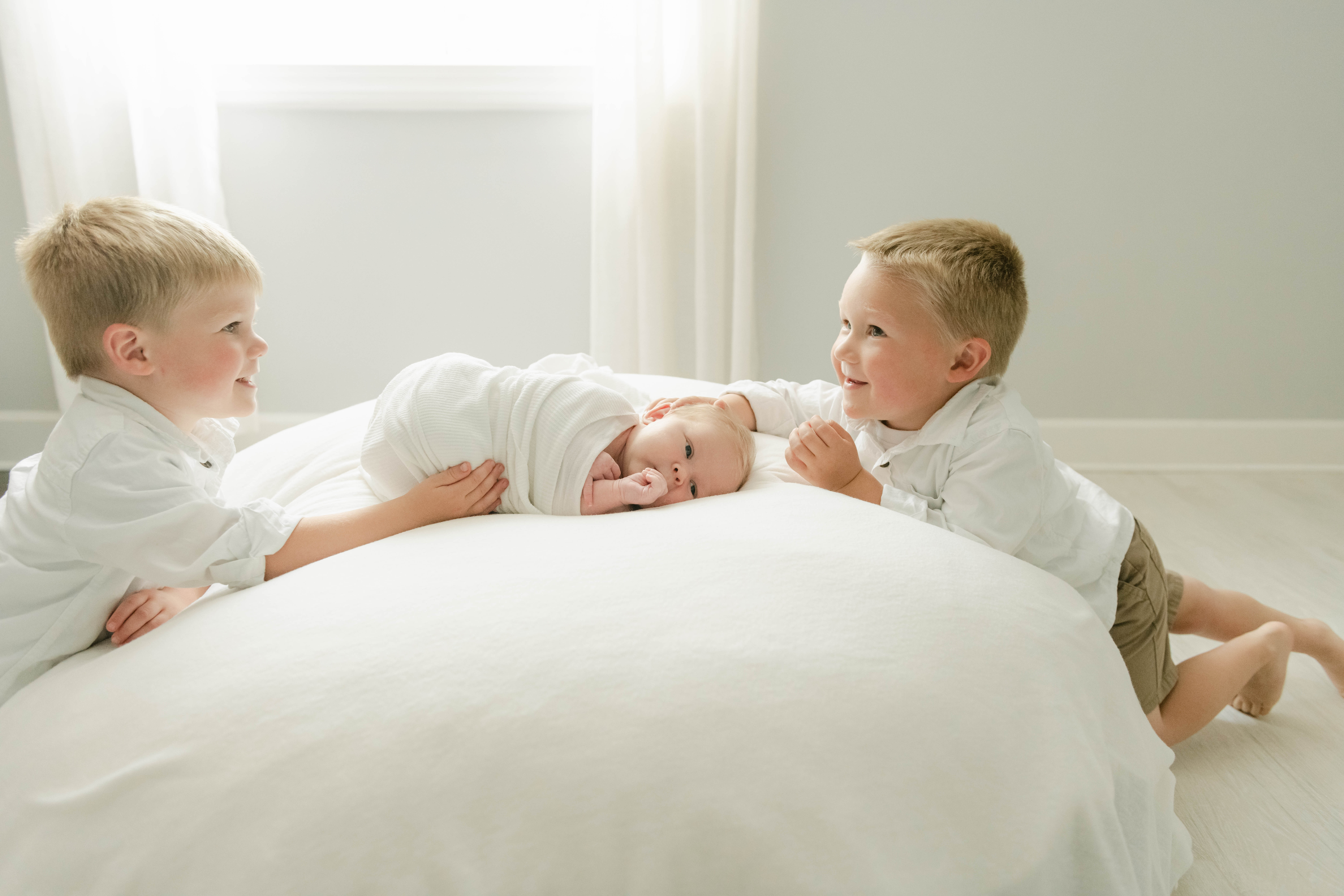 cute big brothers with newborn in white West Chester, pa studio by Valerie Maria Photography
