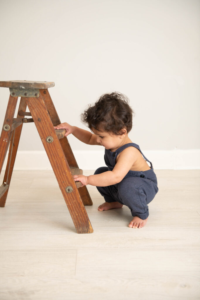 Philadelphia Pediatrician Dr. Meghna Patel baby with ladder in blue 
overalls 
