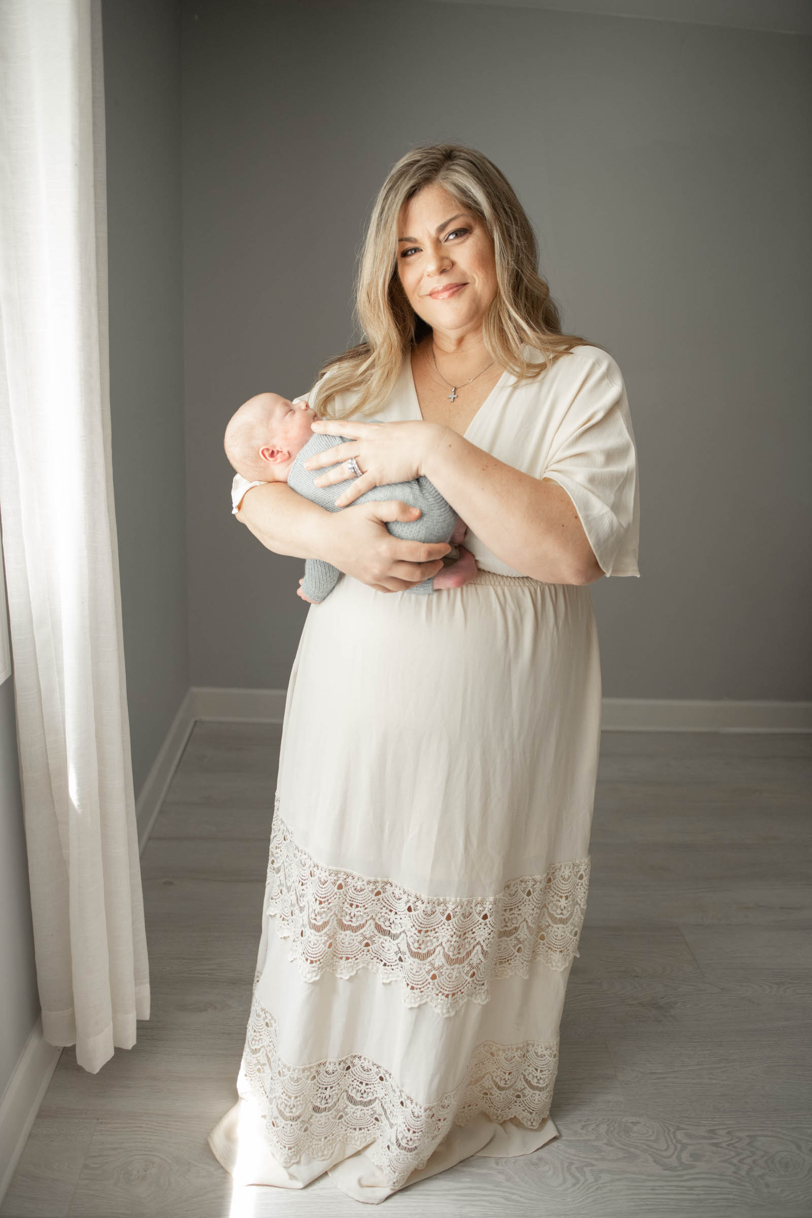 Newborn mother holding baby boy in natural light studio