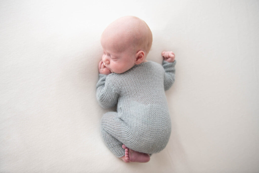 Sleeping baby boy in blue knitted outfit