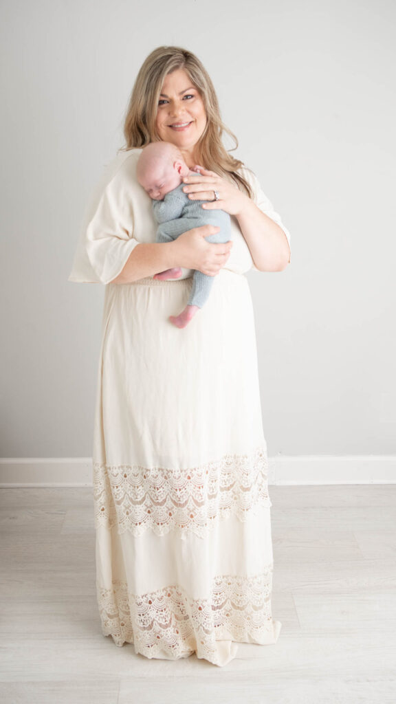 Working mother snuggling baby boy in cream dress