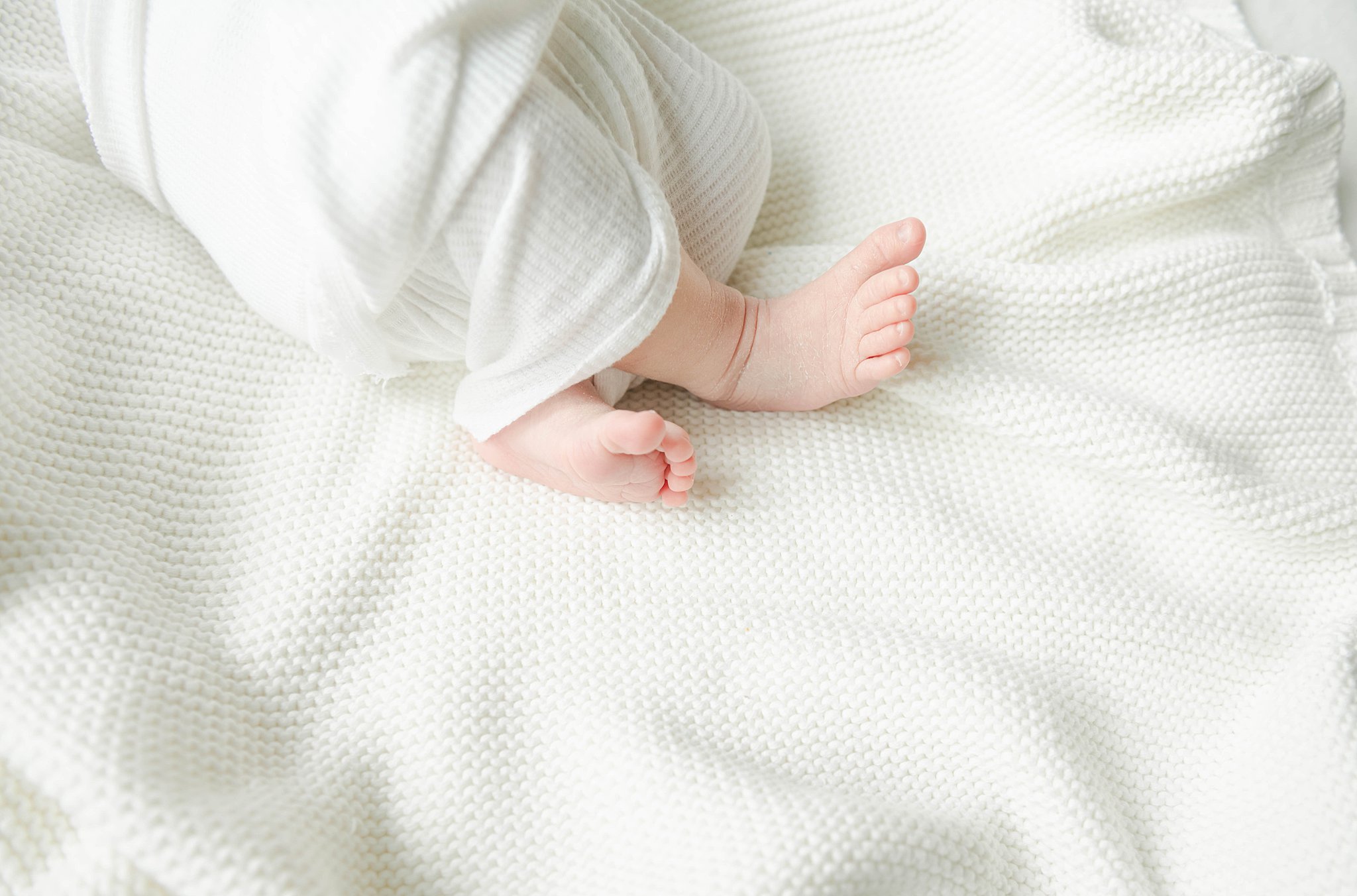 newborn baby feet sticking out of white swaddle on a white blanket lancaster doulas