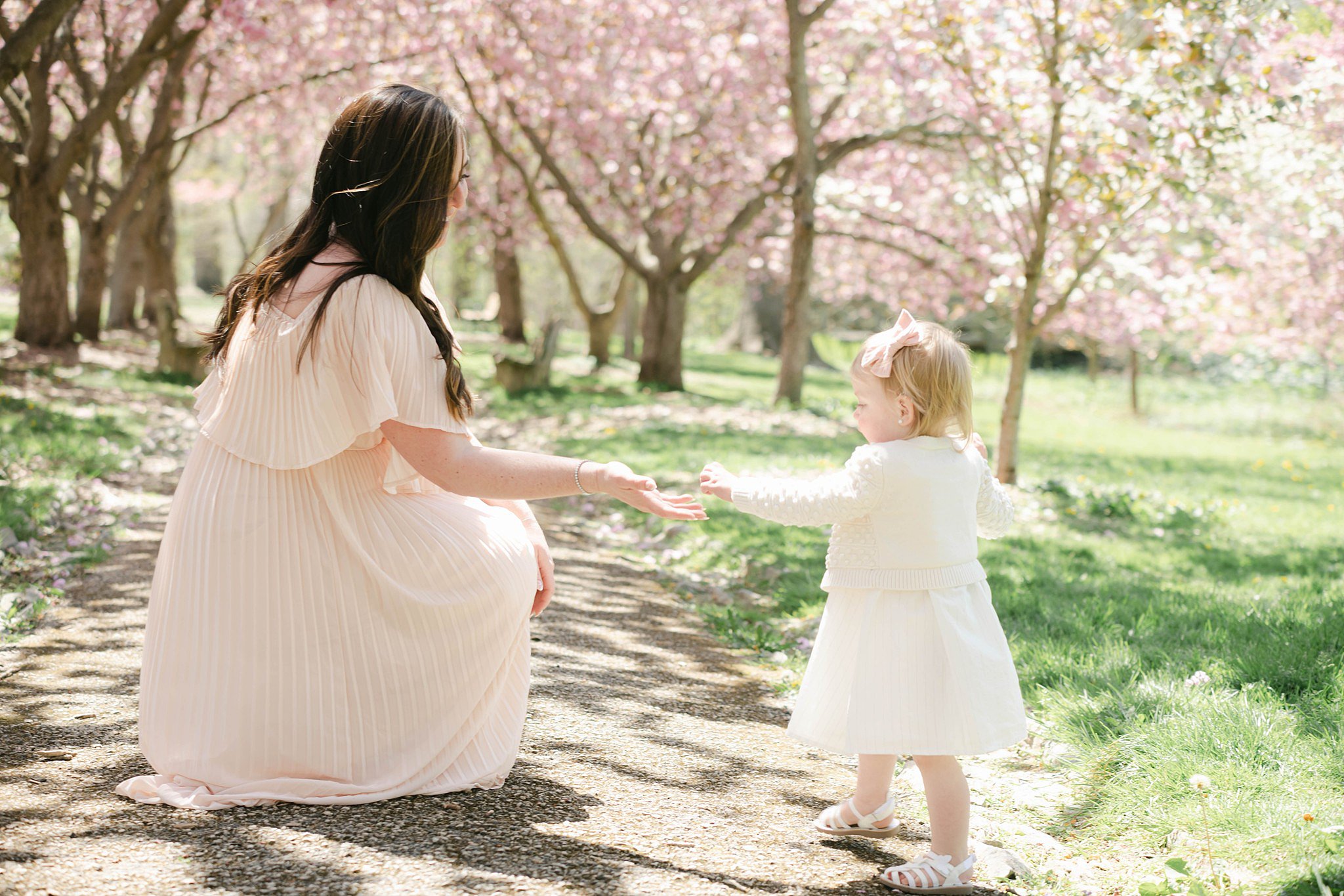 A mother and her young daughter play in a park path