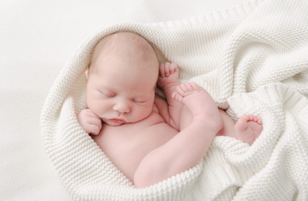 A newborn baby curled up in a white blanket birth center lancaster pa